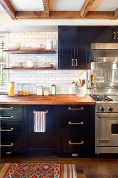 a kitchen with black cabinets and white subway backsplash, stainless steel stove top