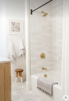 a bathroom with white tile and gold fixtures