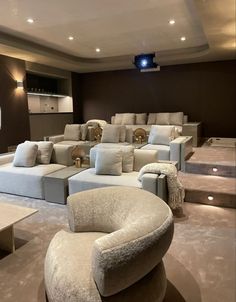 a large living room filled with lots of white couches and chairs in front of a flat screen tv