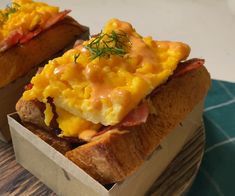 two open faced sandwiches sitting on top of a wooden cutting board next to each other