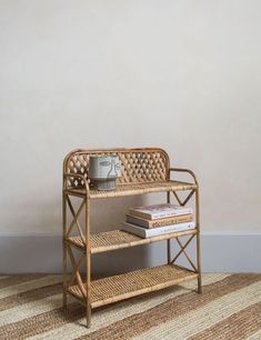 a wicker shelf with books and a cup on it in front of a wall