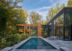 an outdoor swimming pool surrounded by greenery and wooden walls with glass doors on both sides