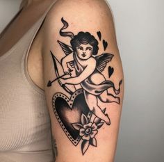 a woman with a tattoo on her arm holding a heart and cupid angel above it