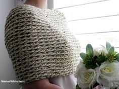 a woman wearing a crochet shawl next to a bouquet of white flowers