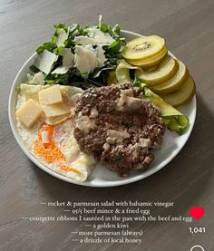 a white plate topped with meat and veggies on top of a wooden table