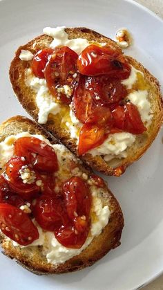 two pieces of bread with tomatoes and cheese on them are sitting on a white plate