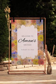 a welcome sign sitting on top of a wooden floor next to a vase filled with flowers