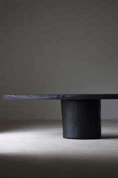 a black table with a knife on it in the middle of an empty room,