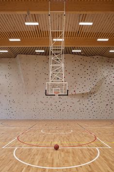 an indoor basketball court with climbing walls and ladders on the wall to climb up