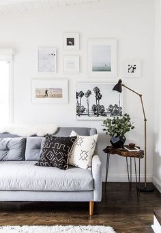 a living room with white walls and pictures on the wall above the gray couches