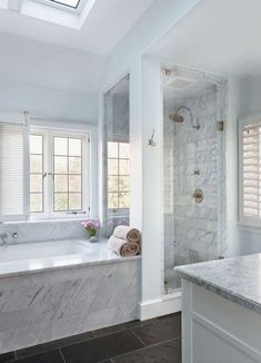 a bathroom with marble counter tops and white walls, along with a walk in shower