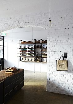 a store with white brick walls and shelves filled with bottles, breads and pastries