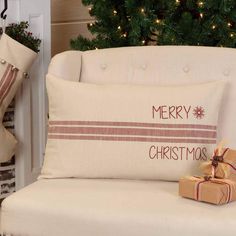 a christmas pillow sitting on top of a white couch next to a christmas tree and presents