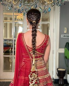 a woman in a red dress is standing with her back turned to the camera and wearing a long braid