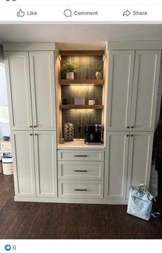 a kitchen with white cupboards and shelves in the center, along with a bag on the floor