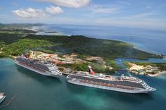 two cruise ships in the water next to each other near an island and blue sky