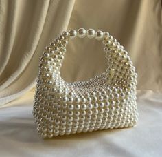 This handmade wedding clutch, adorned with pearl bead details, adds a touch of elegance to your special occasions. Each bead is carefully selected and crafted from high-quality materials. This clutch is the perfect accessory to complement your elegance and style. Designed for Special Occasions Ideal for weddings, engagement ceremonies, balls, and other special events, this clutch is meticulously crafted with attention to every detail. The pearl bead embellishments and lace details provide a dazz Cheap Cream Bags With Pearl Handle, Pearl Evening Bag With Pearl Handle For Wedding Guest, Cream Pearl Evening Bag With Pearl Handle, Pearl White Evening Bag With Pearl Handle For Wedding, Handmade Pearl Evening Bag For Wedding, Pearl Beaded Bags For Wedding, Pearl-embellished Handheld Evening Bag, Pearl Beaded Wedding Bags, Wedding Bag With Pearl Embroidery