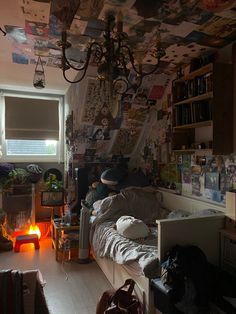 a cluttered room with many pictures on the wall and a lamp hanging from the ceiling