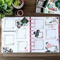 an open planner book sitting on top of a wooden table next to a potted plant