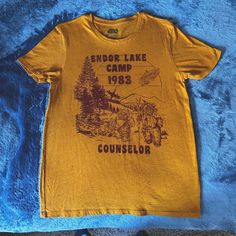 a yellow shirt with an image of a camper and trees on the front that says endo lake camp 1933