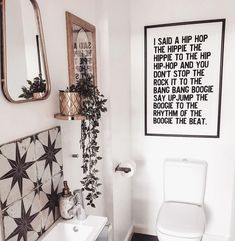 a white toilet sitting next to a bathroom sink under a framed art piece on the wall