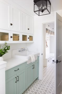 a white bathroom with blue cabinets and a green plant in the corner on the counter