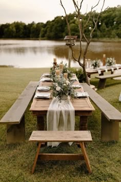 an outdoor table set up with flowers and greenery for a wedding reception by the water