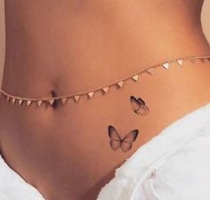 a woman's stomach with butterflies on the side and gold chains around her waist