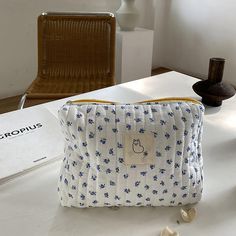 a white and blue purse sitting on top of a table next to a brown chair