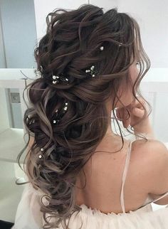 the back of a woman's head with long hair and pearls in her hair