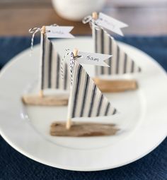 three small wooden sail boats on a white plate