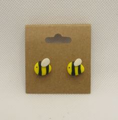 pair of yellow and black bee studs on brown cardboard package with white dots in the background