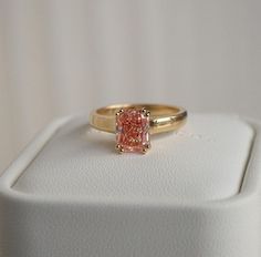 a pink diamond ring sitting on top of a white box