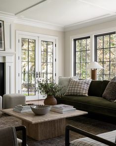 a living room with couches, chairs and a coffee table in front of two windows