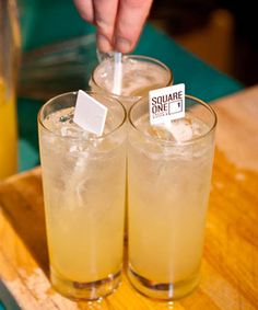 two glasses filled with drinks sitting on top of a wooden tray next to each other