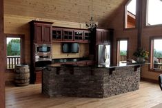 a large kitchen with an island in the middle and lots of wood on the walls