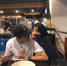 a man and woman sitting at a table with chopsticks in front of them