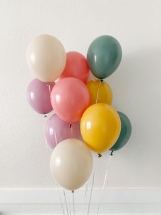 a bunch of balloons floating in the air on top of a table next to a potted plant