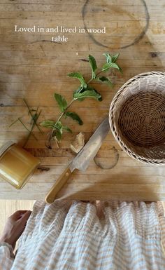 a wooden cutting board topped with a knife next to a potted plant on top of a table