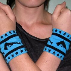 a woman wearing blue and black wristbands with an eye on the side, holding her arm