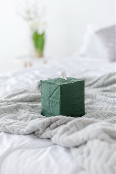 a green box sitting on top of a white bed