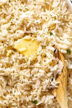 a wooden spoon filled with rice and parmesan on top of a white plate