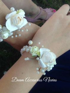 two women wearing bracelets with flowers and pearls on their wristes, one is holding the other