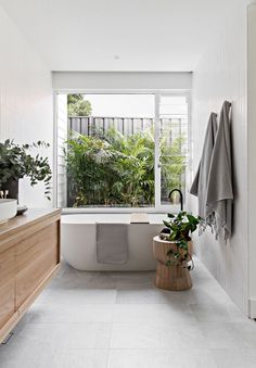 a bathroom with a bathtub, sink and plants in the window sill next to it