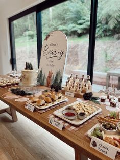 a wooden table topped with lots of food next to a large window filled with windows