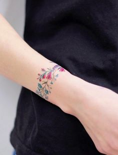 a woman's arm with a flower tattoo on the left side of her wrist