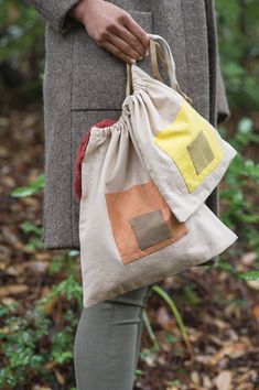 a person holding a bag in their hand while standing on the ground near some trees