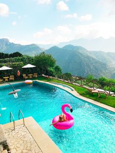 a pool with an inflatable pink flamingo floating on it and mountains in the background