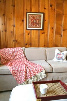 a living room with wood paneling and a couch covered in a red floral blanket