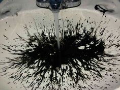 a white sink with black paint splattered all over the bowl and faucet